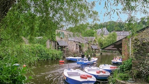 Een gracht met aanmerende boten, omringd door begroeiing en historische gebouwen.