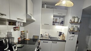 Une cuisine moderne avec des armoires blanches, un comptoir noir, un four encastré et un luminaire suspendu.