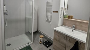 Une salle de bain moderne avec une douche à l’italienne en verre, un lavabo avec un meuble-vasque en bois et un miroir au-dessus du lavabo.