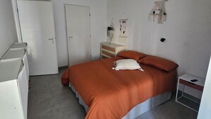 Une chambre à coucher avec un lit, une commode, une table de chevet et une porte.