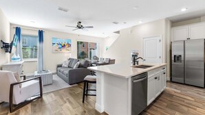 A modern kitchen with white cabinetry, a stainless steel refrigerator, and a central island with a sink. - Flamingo Paradise (Kissimmee)