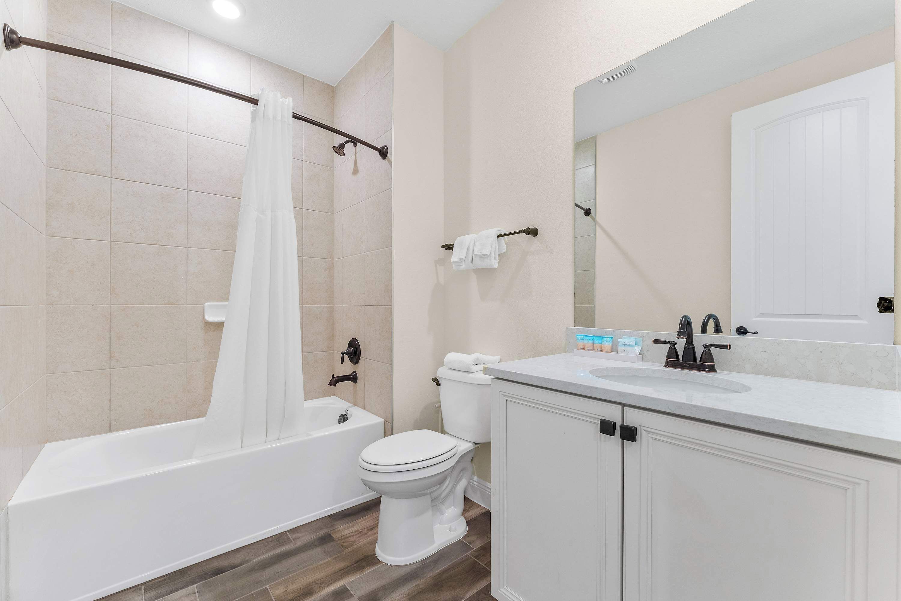 A bathroom with a bathtub, toilet, and vanity with a mirror.