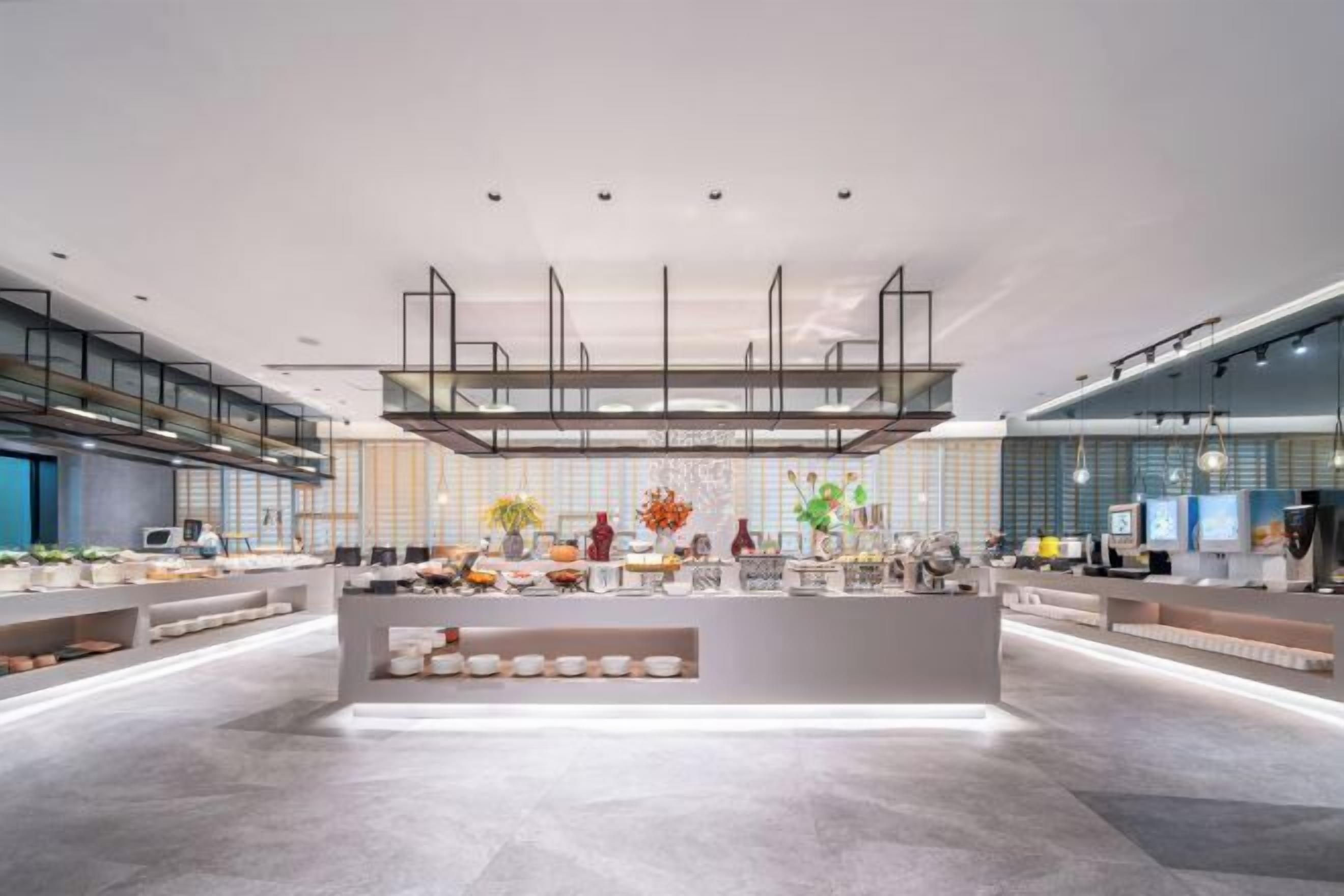 A modern hotel lobby with a central island, seating areas, and a view of the cityscape.