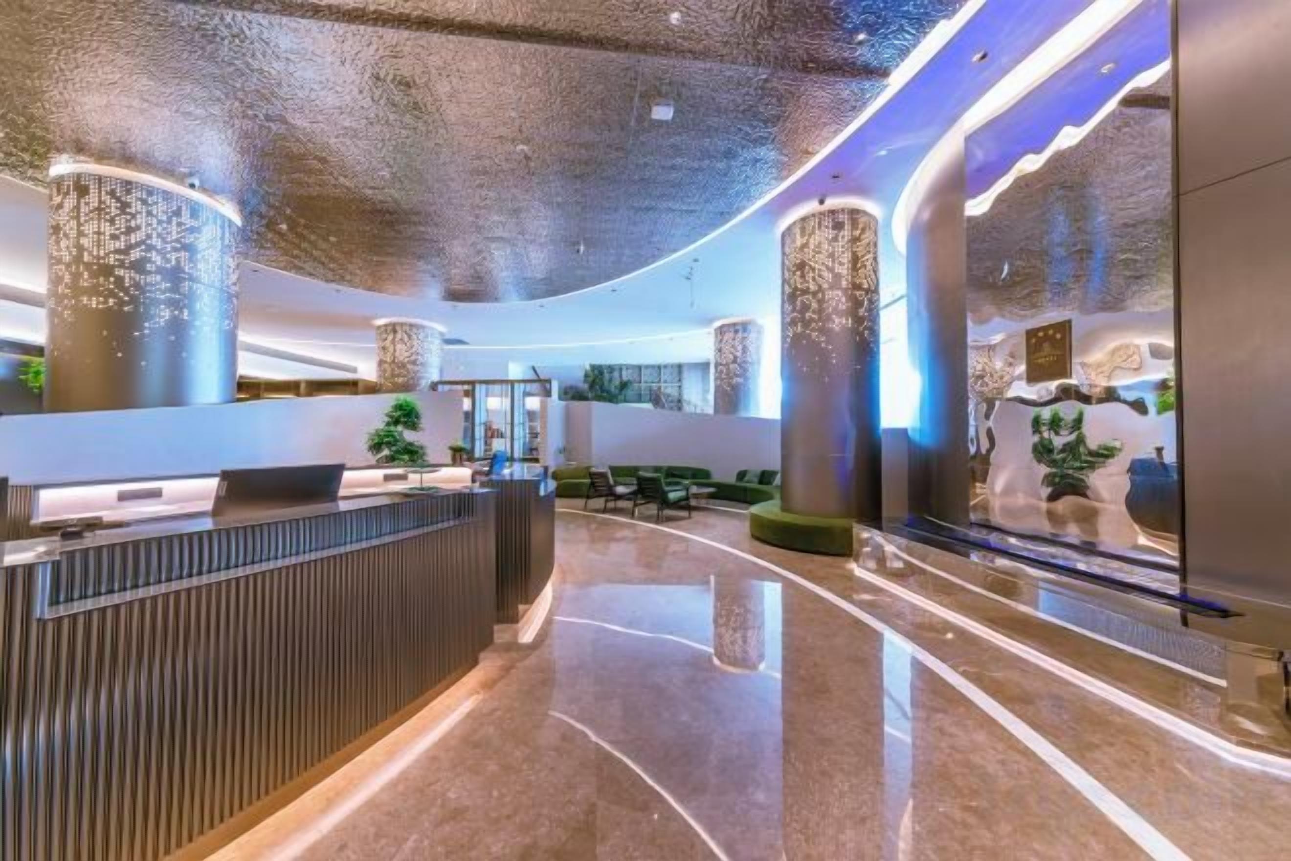A modern hotel lobby with a reception desk, seating area, and decorative pillars.