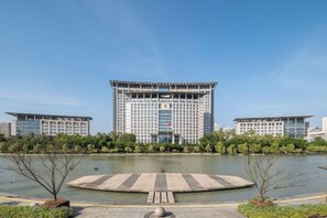 A modern building with a central courtyard and a circular water feature in front. - Radow Wanrong Hotel (Wenzhou)