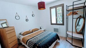 Une chambre à coucher comprenant un lit, une commode, une armoire et une lampe suspendue.