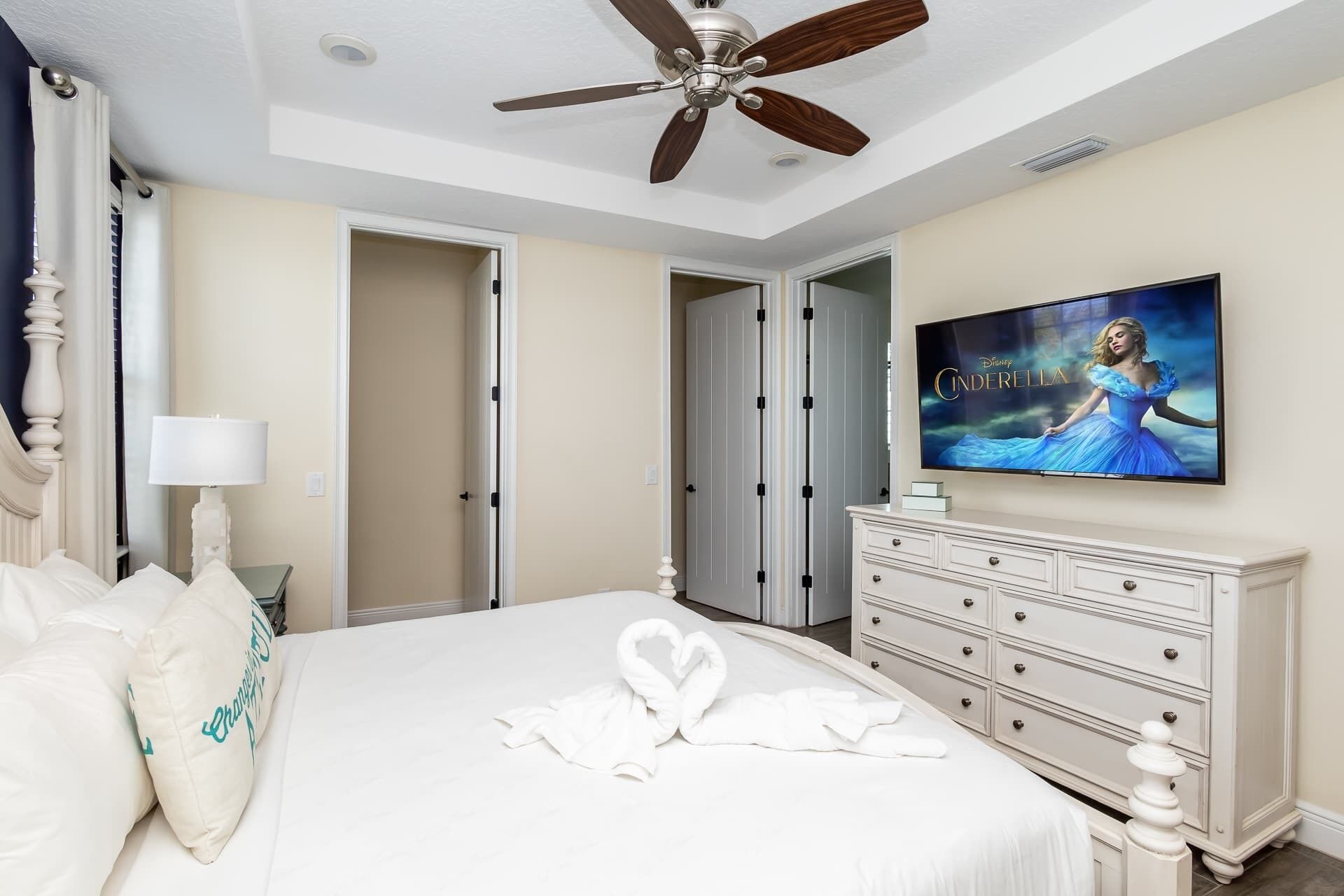 A hotel room with a bed, a television, a dresser, and a ceiling fan.