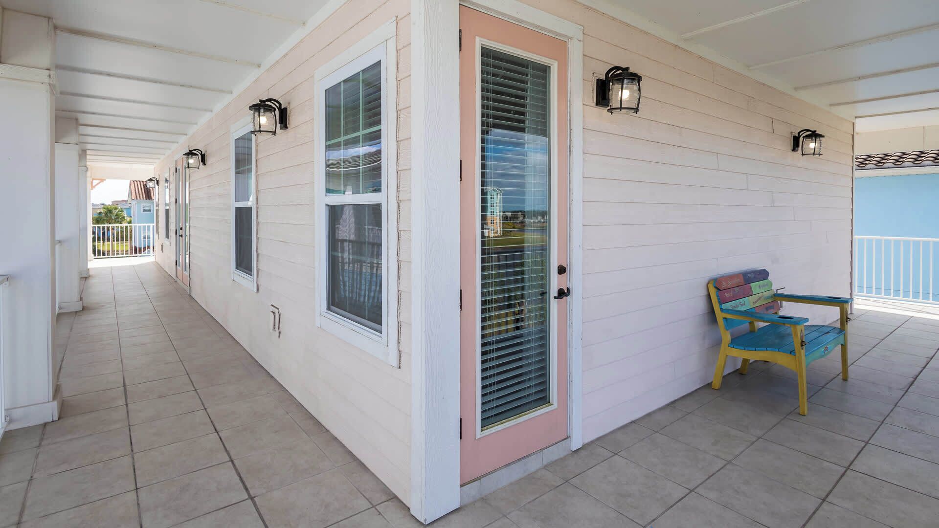 A covered porch with a tiled floor, a door with a window, and a bench.