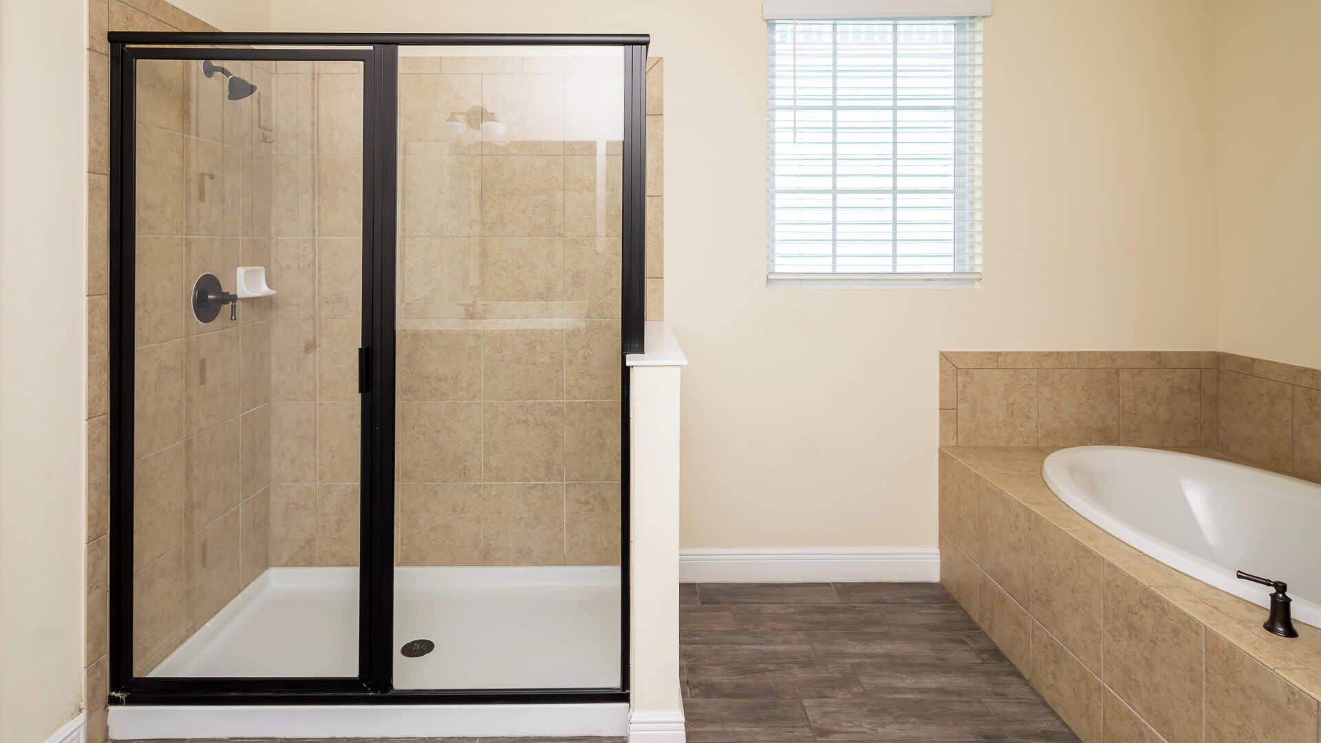 A bathroom with a glass-enclosed shower, a freestanding bathtub, and a window providing natural light.
