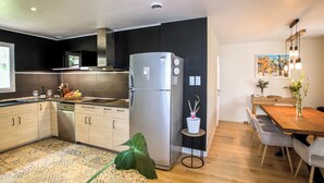 Een moderne keuken met een roestvrijstalen koelkast, houten kasten en een eethoek met een houten tafel en stoelen.
