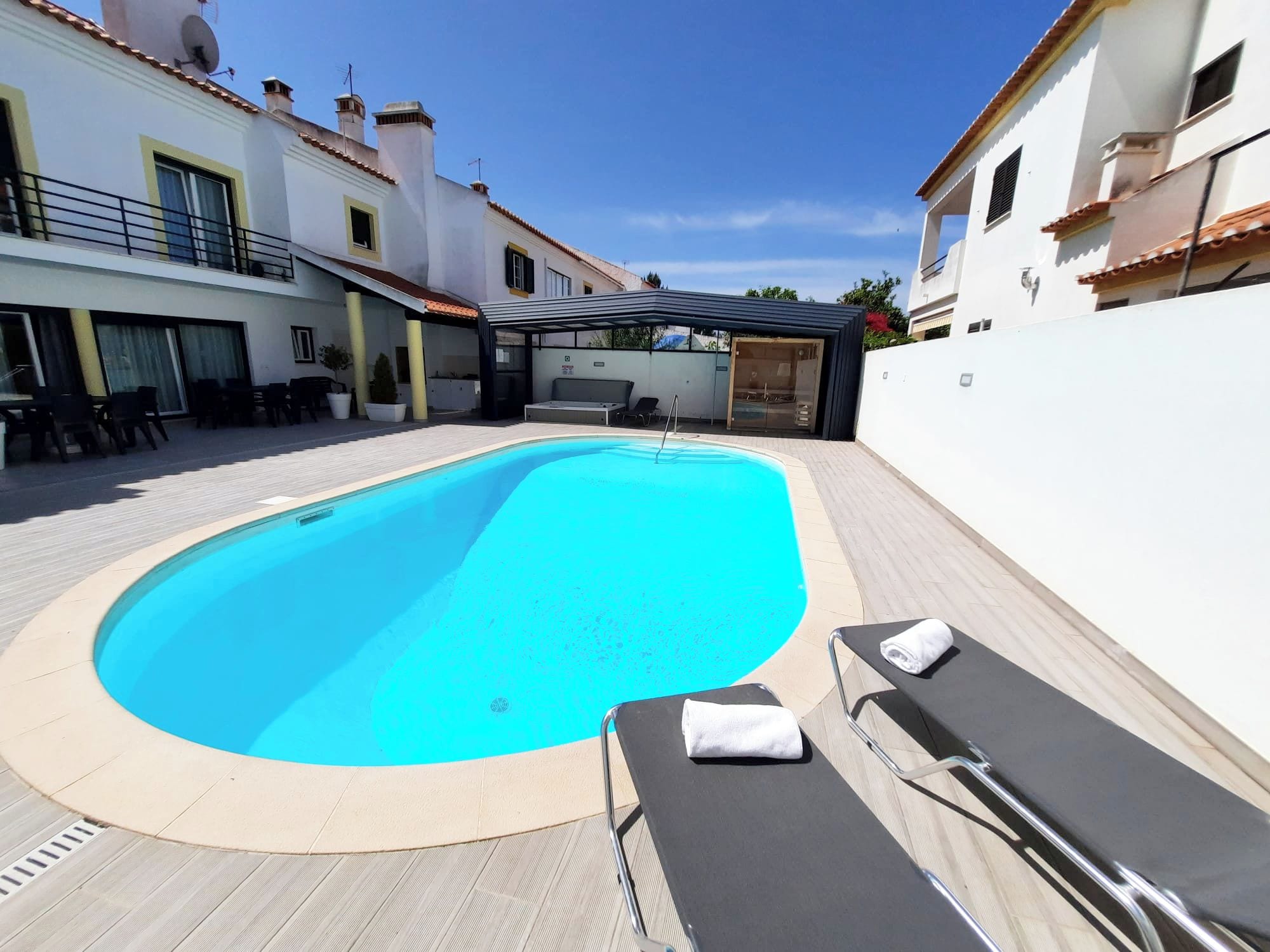 A swimming pool with lounge chairs and a covered seating area.