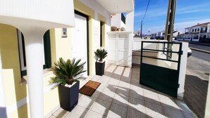 A modern building with a gated entrance, potted plants, and a tiled floor. - Milfontes Guest House (Odemira)
