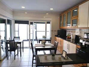 Una cucina moderna con mobili in legno, un piano di lavoro nero e un forno integrato. C'è una zona pranzo con tavolo e sedie, e un'ampia finestra che offre luce naturale.