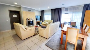 A modern living room with a sofa set, a TV, and a dining area with a table and chairs. - Milfontes Guest House (Odemira)