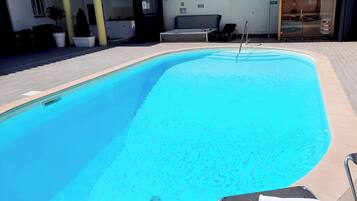 A swimming pool with a lounge chair and a towel, surrounded by a covered patio area.