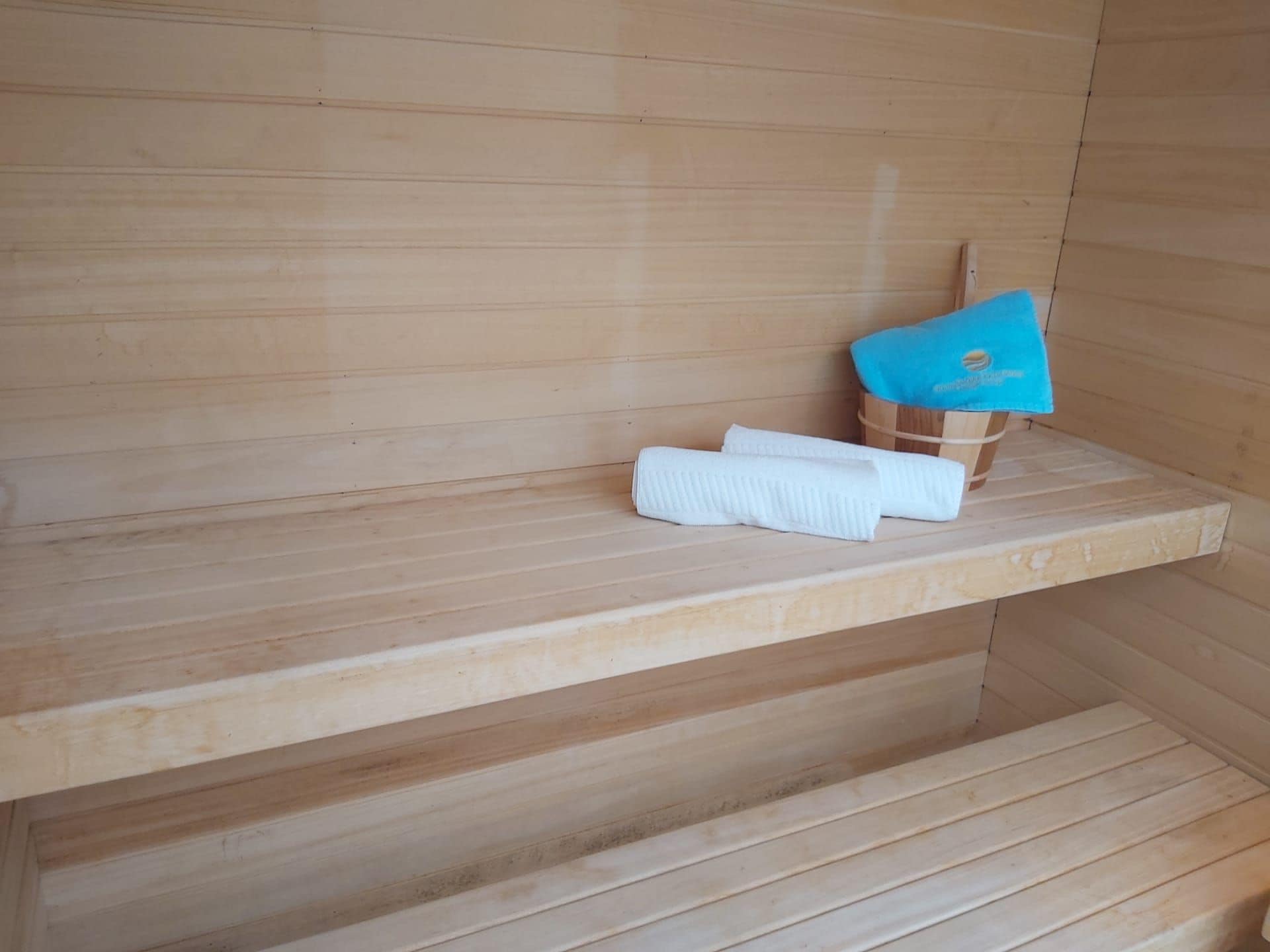 A wooden bench with a towel and a blue bag.