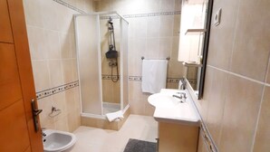 A bathroom with a shower, sink, toilet, and a mirror. - Milfontes Guest House (Odemira)