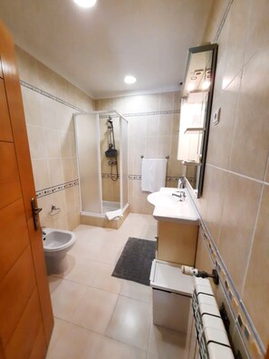 Un bagno con doccia, lavandino, WC e uno specchio.