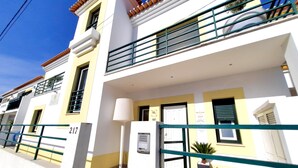 A multi-story building with balconies, a ground floor entrance, and a visible door number. - Milfontes Guest House (Odemira)