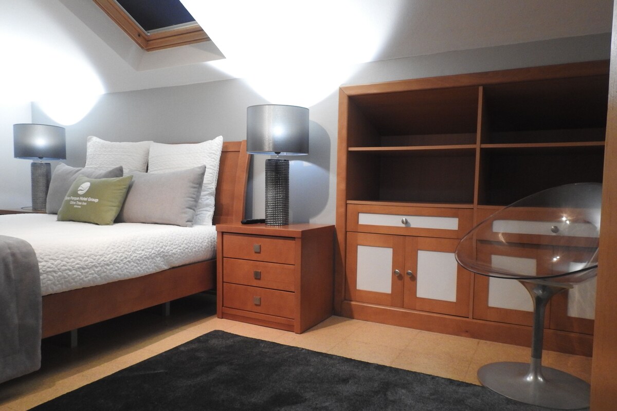 A bedroom with a bed, bedside tables, a wardrobe, and a glass table.