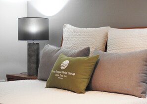 Un lit avec plusieurs oreillers, une lampe et un logo sur un oreiller.