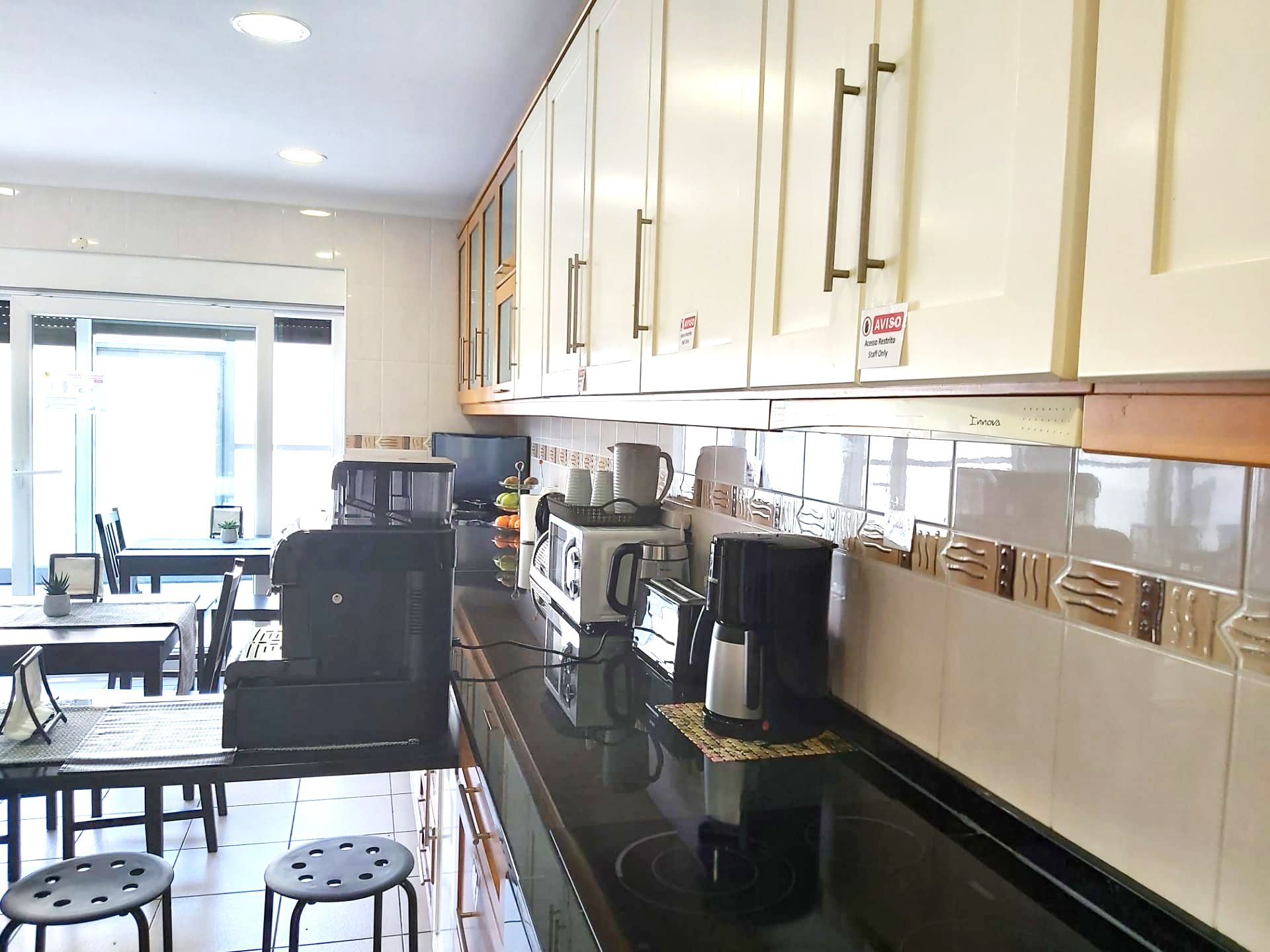 A modern kitchen with white cabinets, a black countertop, and a dining area with a table and chairs.