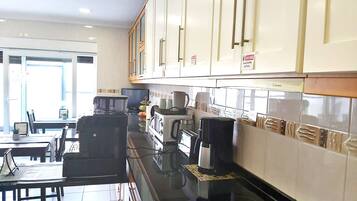 A modern kitchen with white cabinets, a black countertop, and a dining area with a table and chairs.