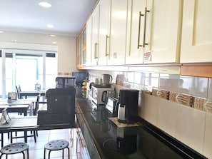 Una cocina moderna con armarios blancos, encimera negra y un comedor con mesa y sillas.
