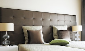 A hotel room with a tufted headboard, two bedside lamps, and a bed with a quilted cover. - Milfontes Guest House (Odemira)