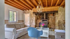 A cozy living room with a stone fireplace, a sofa, a blue chair, and a glass table with flowers.