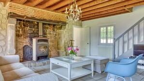 A cozy living room with a stone fireplace, a glass coffee table, a sofa, and a blue chair.