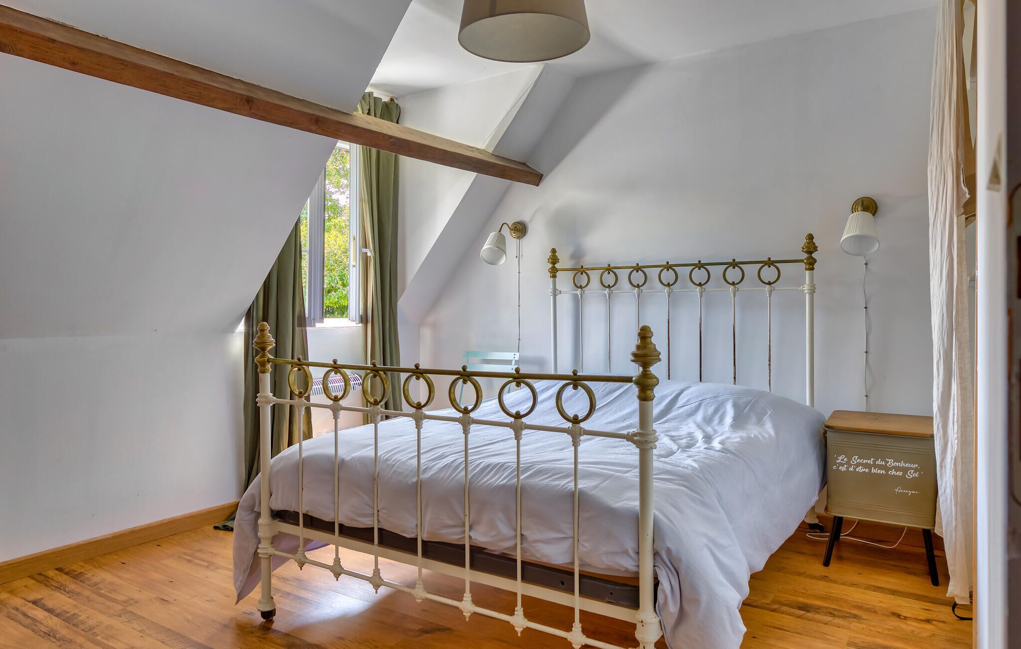 Un dormitorio con una estructura de cama de metal blanco, una mesita de noche de madera y una pequeña mesa.