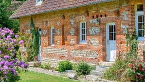 A brick house with a tiled roof, a front door, and a small porch area.