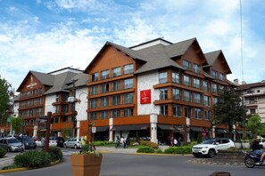 A multi-story hotel with a brick facade, large windows, and a central entrance. - Come and discover the Hotel Laghetto Stillo Borges (Centro Gramado)