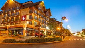 Et hotel med flere etager, varm facade, store vinduer og en veloplyst indgang.