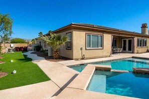 Una propiedad residencial con piscina, patio y un césped bien cuidado.