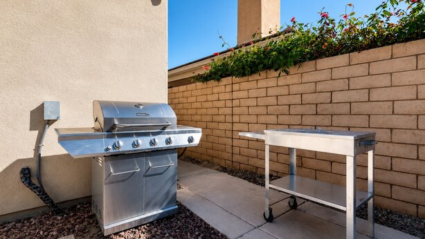 Un barbecue d’extérieur avec une table d’appoint, placé contre un mur de briques et sous un ciel dégagé.