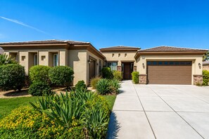 A residential property with a driveway, a garage, and a well-maintained lawn with various plants. - Indio 4000 SQ FT 5bedroom. 3 BATH, SALT, POOL , SPA, WiFi and AC, COACHELLA, (Indio)