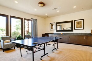 A room with a ping pong table, a chair, a cabinet, and a large mirror on the wall. - Indio 4000 SQ FT 5bedroom. 3 BATH, SALT, POOL , SPA, WiFi and AC, COACHELLA, (Indio)