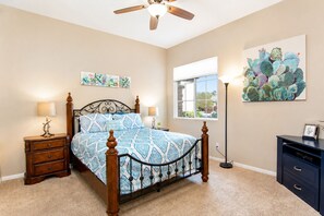 A bedroom with a bed, bedside tables, a nightstand, a floor lamp, a window, and artwork on the walls. - Indio 5BR Desert Oasis, Sleeps 14, Private Saltwater Pool and Spa (Indio)