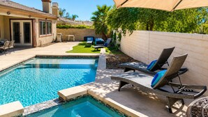 Un jardin avec une piscine, des chaises longues et un patio couvert.