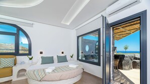 Un dormitorio moderno con una cama curva, ventanas amplias y vistas al mar.