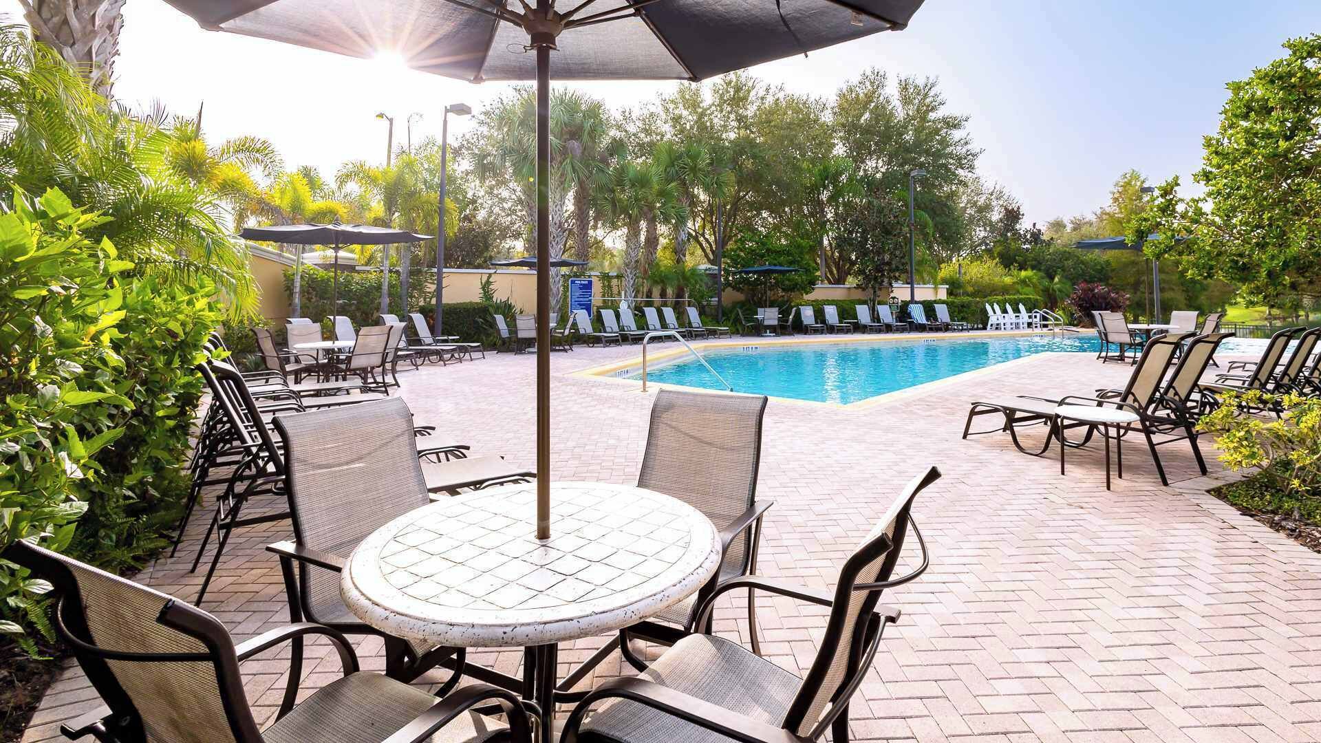 A poolside area with lounge chairs, a table, and umbrellas.