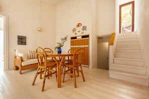 Un espace repas comprenant une table et des chaises en bois, un canapé, un meuble et un escalier.