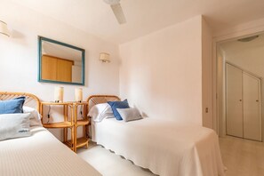 A bedroom with two single beds, a bedside table with lamps, a mirror, and a wardrobe. - BLUE BAY HOME just few steps from the bay of Porto Luna (Villasimius)