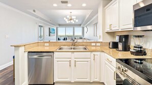 A modern kitchen with white cabinetry, stainless steel appliances, and a granite countertop. - Lake Views At Blue Heron (Orlando)