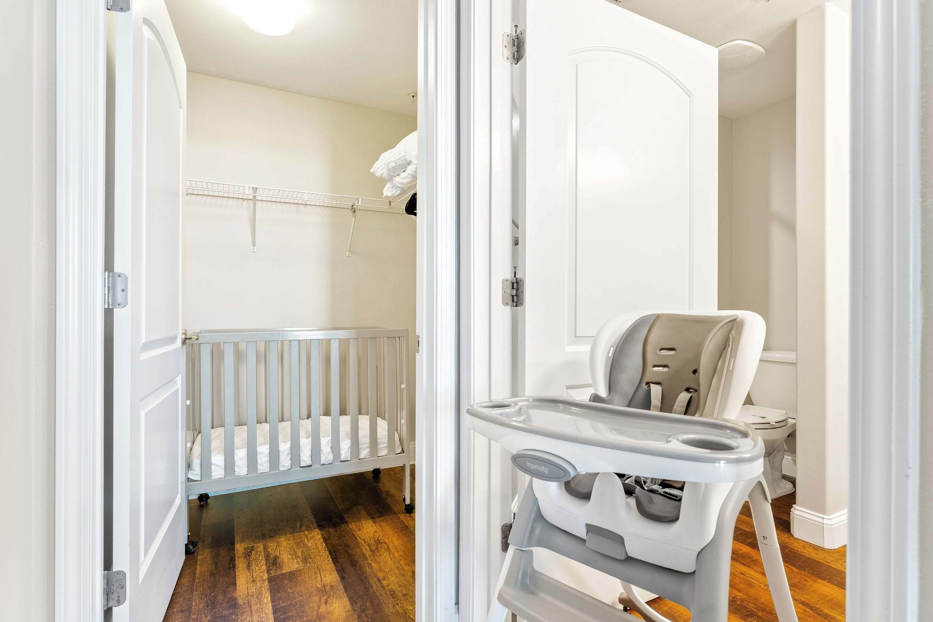 A baby room with a crib, a high chair, and a toilet.