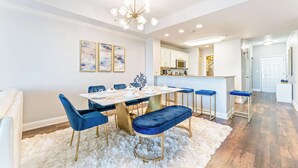 A modern dining area with a white table, blue chairs, and a fluffy white rug. - Lake Views At Blue Heron (Orlando)