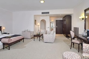 A hotel room with a bed, two armchairs, a sofa, a dining table, and a mirror. - Melia Grand Hermitage (Golden Sands)