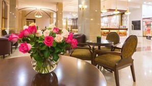 A hotel lobby with a round table, chairs, and a vase of pink and white roses. - Melia Grand Hermitage (Golden Sands)